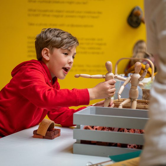 A child playing with a human figure mannequin.