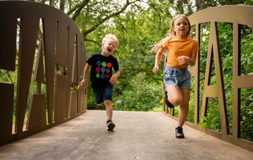 Two children running along a metal bridge towards the camera.