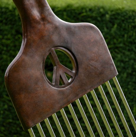 Detail of sculpture of an oversized afro pick, displayed outdoors, with a peace sign in the centre.