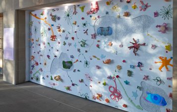 A white wall covered in colourful shaped objects and film screens.