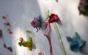 Close up of flower shaped rubber objects displayed on a white wall.