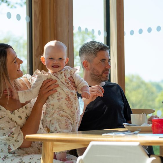 A family with a baby, eating at a table in the restaurant.
