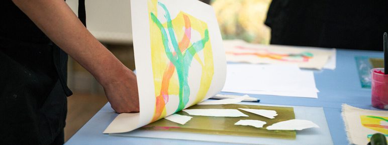 Close up of a person making a colourful print using gelli techniques.